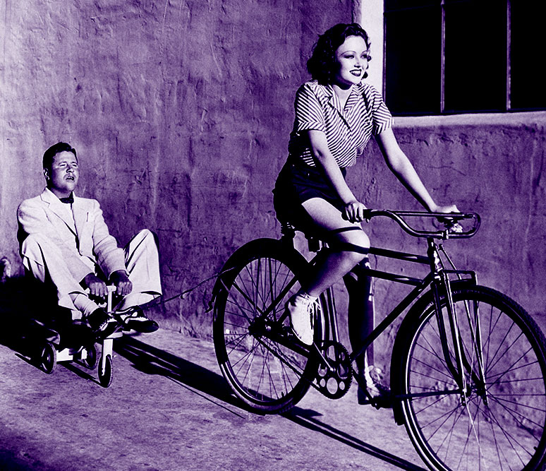 woman riding a bike towing a man on a tricycle